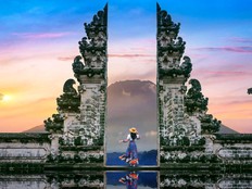 A young woman stands at the temple gates at Lempuyang Luhur temple in Bali, Indonesia, in this stock photo.