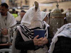 Covered in prayer shawls, a Jewish man of the Cohanim Priestly caste participates in a blessing during the holiday of Passover, at the Western Wall, the holiest site where Jews can pray, in the Old City of Jerusalem, Tuesday, April 15, 2025.