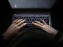 A simple, very dark image of hands typing on a backlit keyboard at night.