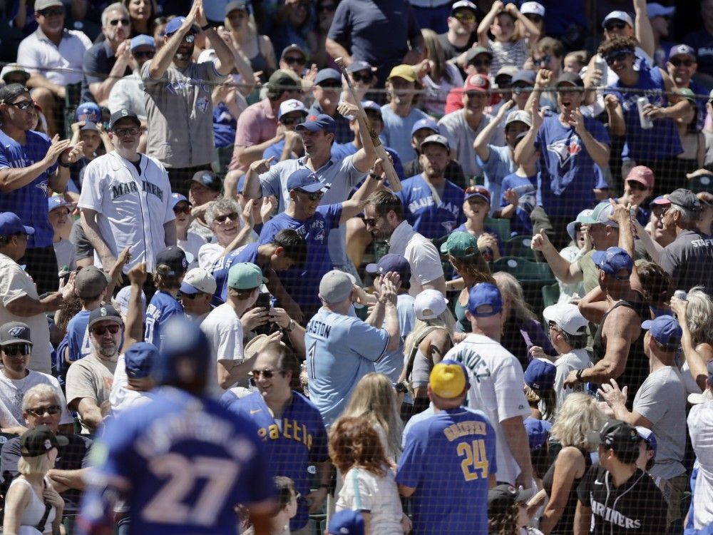 A fan holds up the bat Blue Jays' Vladimir Guerrero Jr. lost on a swing during the fifth inning against the Mariners, July 6, 2024, in Seattle.