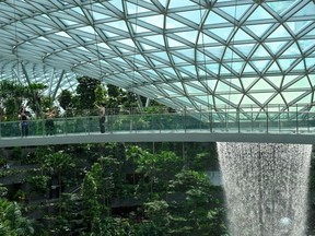 People take picture from a observation bridge of Rain Vortex at Jewel Changi airport in Singapore on December 7, 2022.