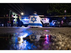 A bystander prays while wearing an Israel flag with a cross in the middle near the Capital Jewish Museum in Washington on Wednesday night. MUST CREDIT: Tom Brenner/For The Washington Post