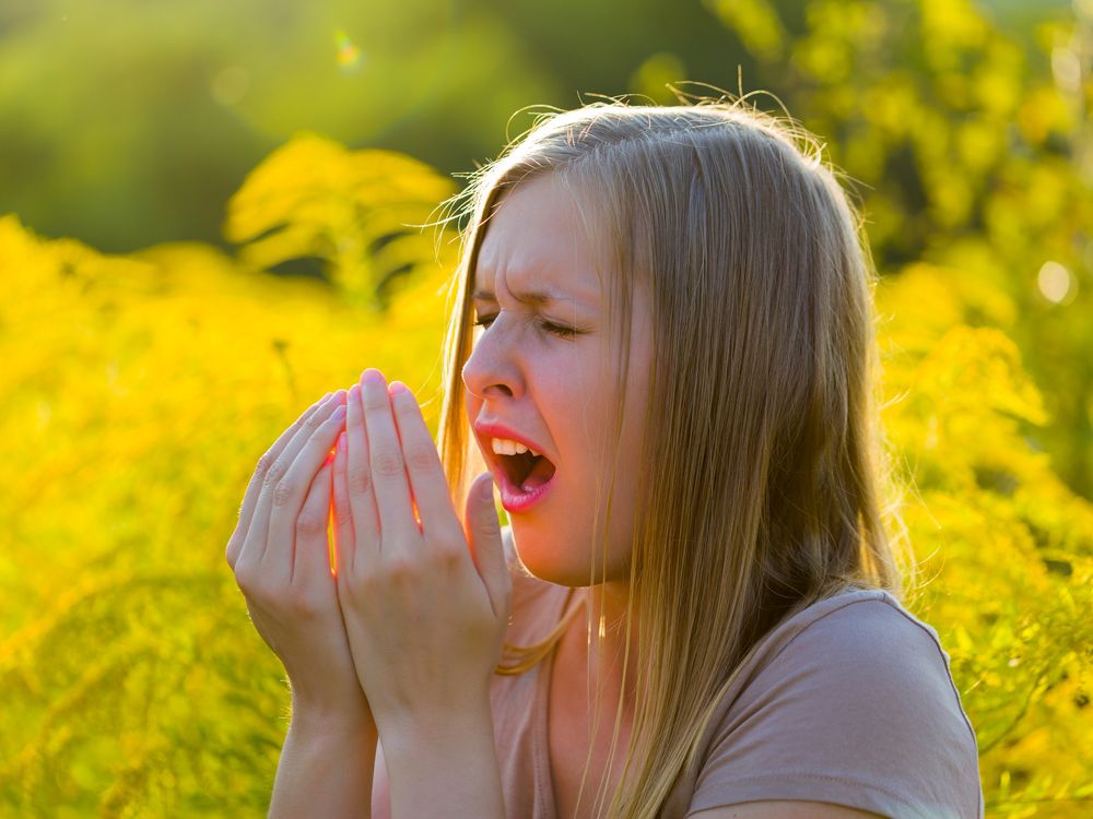 Woman sneezes due to immune system with allergies.