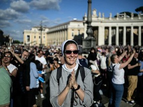 A nun reacts as white smoke (unseen) signals that cardinals elected a new pope during their conclave in the Vatican on May 8, 2025.
