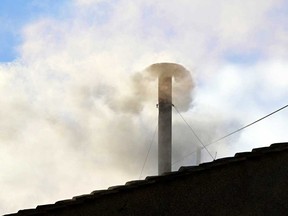 This photograph shows white smoke rising from the chinmey of the Sistine Chapel signaling that cardinals elected a new pope during their conclave in the Vatican on May 8, 2025.