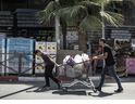 يدفع رجلان كرسي متحرك مليء بالسلع المشتراة لأن الناس لديهم لوازات في القدس في 13 يونيو 2025.