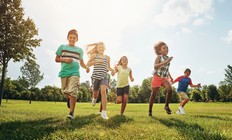 Young kids run outdoors.