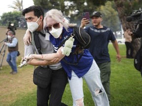 A man helps an injured woman during a protest in the Paramount section of Los Angeles, Saturday, June 7, 2025, after federal immigration authorities conducted operations.