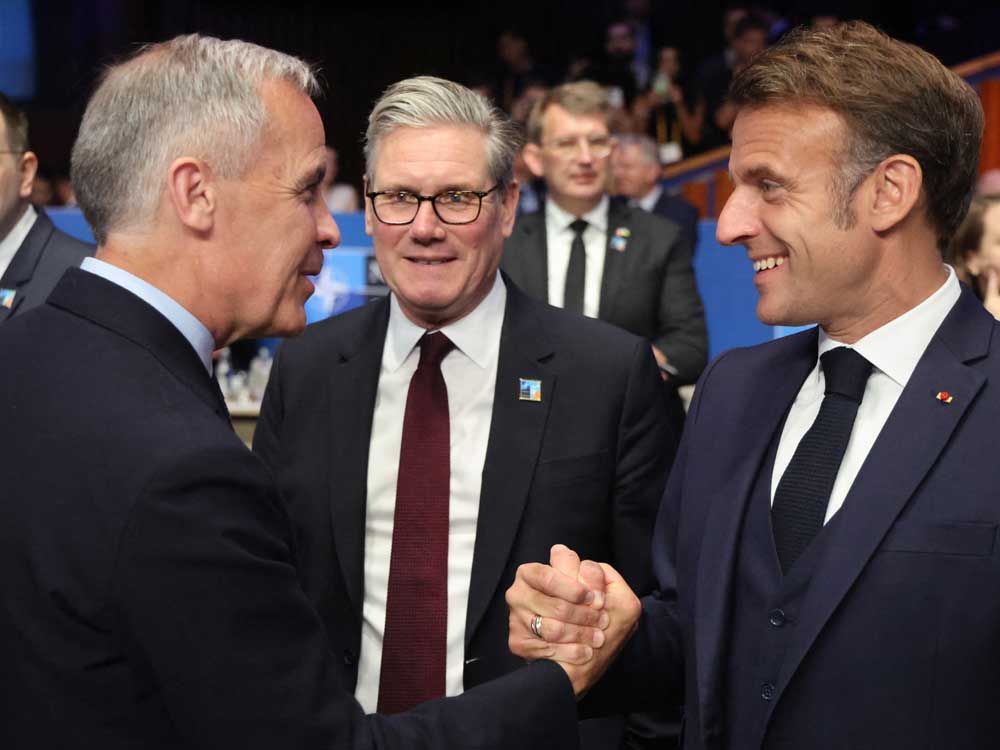 France's President Emmanuel Macron (right) shakes hands with Canada's Prime Minister Mark Carney (left) as Britain's Prime Minister Keir Starmer (centre) looks on before the start of the North Atlantic Council plenary meeting at the North Atlantic Treaty Organization (NATO) summit in The Hague on June 25, 2025. 