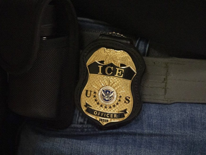 A federal agent wears a badge of Immigration and Customs Enforcement while standing outside an immigration courtroom at the Jacob K. Javits Federal Building in New York, Tuesday, June 10, 2025.