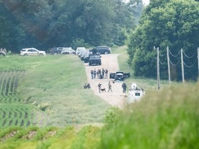 Law enforcement search the area around a vehicle on 301st Avenue on June 15, 2025 in Belle Plaine, Minn.