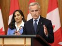 Canadian Prime Minister Mark Carney (R), flanked by Canadian Foreign Affairs Minister Anita Anand, speaks during a press conference after a Cabinet meeting to discuss both trade negotiations with the US and the situation in the Middle East, at the National Press Theatre in Ottawa on July 30, 2025.