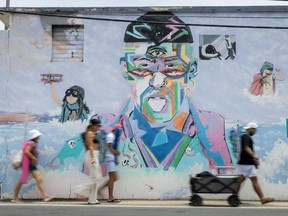 People on their way to the beach walk past a mural of Puerto Rican singer Bad Bunny in Vega Baja, Puerto Rico, the municipality where the global superstar grew up. (Ricardo ARDUENGO/AFP)