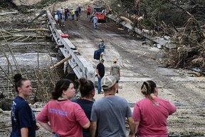 People look on as law enforcement and volunteers continue to search for missing people near Camp Mystic, the site of where at least 20 girls went missing after flash flooding in Hunt, Texas, Saturday July 5, 2025.
