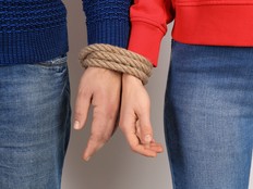 Couple with tied together hands on light background. Concept of addiction