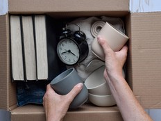 Person's hands placing used personal belongings items into cardboard box