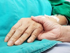 The hand of a patient on a bed is being held