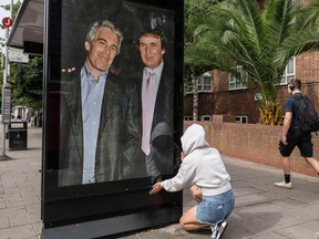 Activists put up a poster showing President Donald Trump and Jeffrey Epstein near the U.S. Embassy in London, Thursday, July 17, 2025.