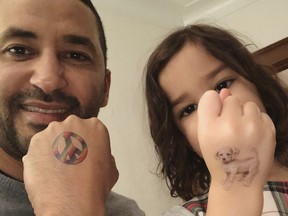 Luciano Frattolin and daughter Melina in 2023 showing off tattoos on hands.