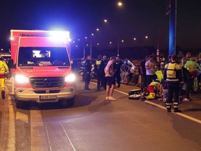 First responders treat injured people on a bridge after fireworks exploded near spectators during the final fireworks display at the Rhine funfair in Duesseldorf, Germany, Friday, July 18, 2025.