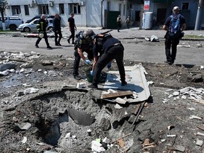 Ukrainian law enforcement officers work next to a crater following a drone attack in Kharkiv on July 7, 2025, amid the Russian invasion of Ukraine.