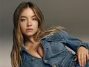 Sydney Sweeney in denim jacket and jeans, lying on floor in American Eagle ad campaign.