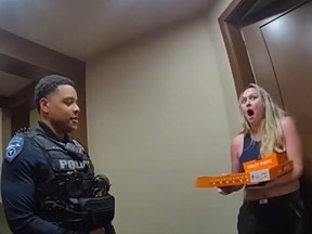 Tempe police officer and shocked customer holding pizza box and another food box after womans delivery driver was arrested and cops completed the delivery.
