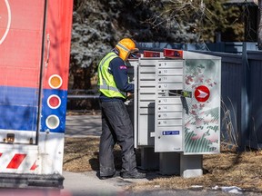 A Canada Post mail carrier delivers to a community mailbox in Calgary on Tuesday, March 18, 2025.
