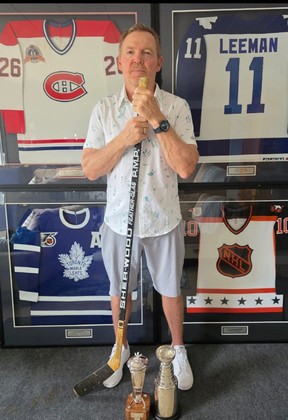 Former NHLer Gary Leeman poses in front of his jerseys and trophies.