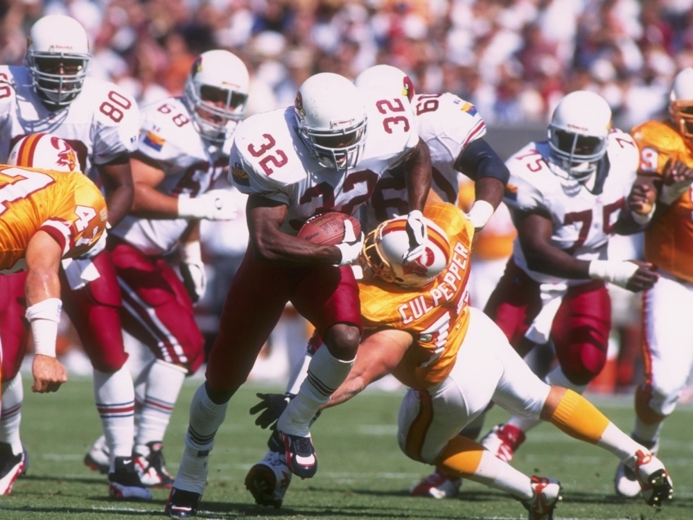 Running back LeShon Johnson of the Arizona Cardinals uses his left arm in attempt to break through the grasp of defensive lineman Brad Culpepper of the Tampa Bay Buccaneers during a game in 1996.
