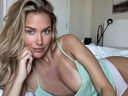 Golf influencer Paige Spiranac poses for a photo lying in bed.
