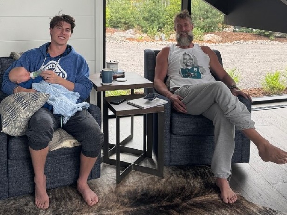 Mitch Marner holds his child while sitting next to Joe Thornton.