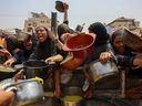 Palestinians gather to receive cooked meals from a food distribution centre in Gaza City on Aug. 13, 2025. Israeli military said it had approved the framework for a new offensive in the Gaza Strip, as Hamas condemned what it called