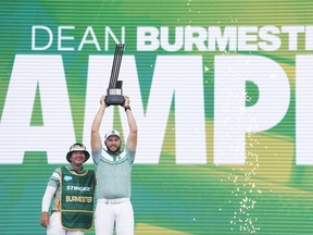 Dean Burmester holds a golf trophy.