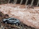 A damaged car lies abandoned along the banks of an overflowing Tawi river after heavy rain showers induced a rise in its water level in Jammu on August 27, 2025.