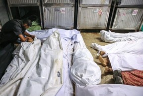 A Palestinian man at the morgue of at Al-Shifa hospital in Gaza City mourns over the shrouded body of a loved one killed while seeking aid near Zikim in the northern Gaza StripOmar AL-QATTAA/AFP