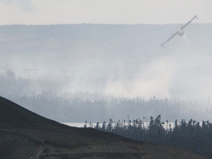 A water bomber flies over a wildfire near St. John's, N.L., on Wednesday, Aug. 13, 2025.