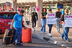 Travellers pass Air Canada flight attendants on strike at Pearson International Airport in Toronto on Saturday, Aug. 16, 2025.