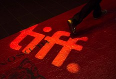 A man walks on a red carpet displaying a sign for the Toronto International Film Festival at the TIFF Bell Lightbox in Toronto.