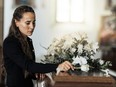 Funeral, sad and woman with flower on coffin after loss of a loved one, family or friend. Grief, death and young female putting a rose on casket in church with sadness, depression and mourning