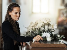 Funeral, sad and woman with flower on coffin after loss of a loved one, family or friend. Grief, death and young female putting a rose on casket in church with sadness, depression and mourning