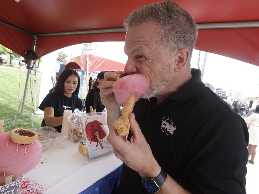 The 146th edition of the Canadian National Exhibition has something for everybody and Wednesday's kick-off highlighted all the crazy food concoctions, plus some iconic staples. (Pictured) CNE CEO Mark Holland bites into the Bacone, a spicy Habanero Bacon Cotton Candy creation topped with an all-Canadian butter tart made by the Greenery Bakeshop.  On Aug. 13, 2025. (Jack Boland,Toronto Sun)