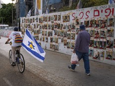 Cyclist with Israeli flag goes past images of Israeli hostages