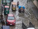 Vehicles and motorcyclists drive through a flooded road after heavy rainfall in Peshawar, Pakistan, Monday, Aug. 18, 2025.
