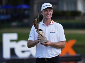 Justin Rose holds a golf trophy.