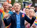 Prime Minister Mark Carney fans himself while he marches in the Vancouver Pride Parade in Vancouver, on Sunday, Aug. 3, 2025.