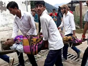 An injured person is carried to a hospital after torrents of water slammed into a Himalayan mountain village in Indian-administered KashmirImran Shah/AFP
