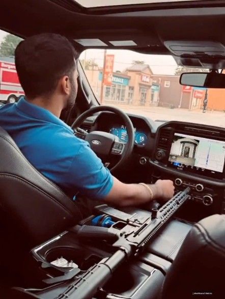 A gun is shown inside a vehicle with an unknown individual. SCREEN GRAB