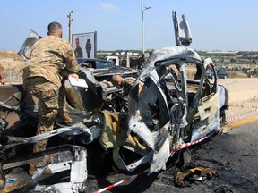 Lebanese army soldiers check the wreckage of a vehicle that was reportedly targeted by an Israeli strike, on the highway near the village of Ansarieyh, south of the coastal city of Sidon on Aug. 8, 2025.