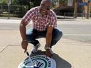 Councillor Chris Moise installs a “walk your bike” decal on a sidewalk in his Toronto Centre ward.